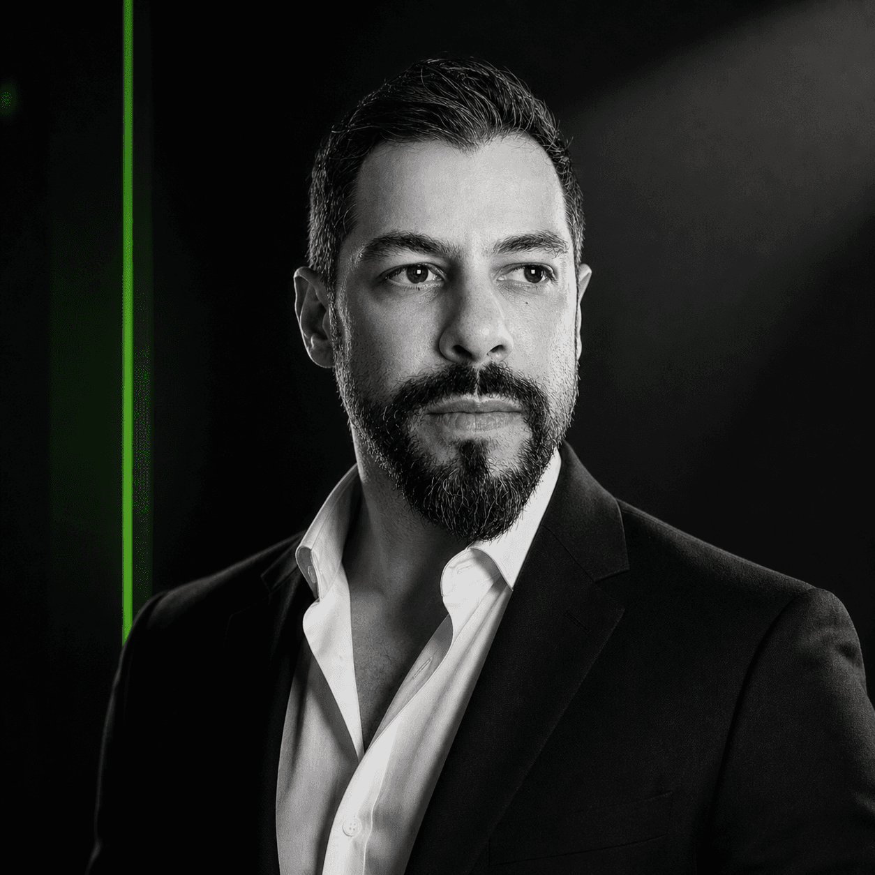 Retrato em preto e branco de Thiago Felizola, fundo escuro com neon verde